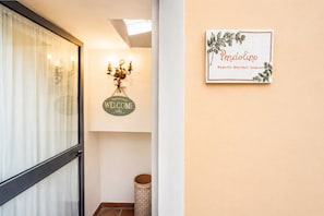 Ein Flur mit einem 'Welcome'-Schild, einem gerahmten Willkommensschild und einem Mülleimer.