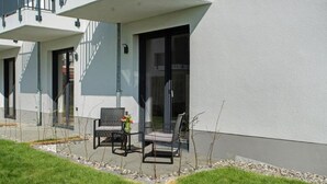 A modern building with a balcony, outdoor seating, and a clear view of the sky.