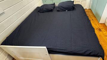Een eenpersoonsbed met een wit frame en een zwarte matras, voorzien van twee kussens.