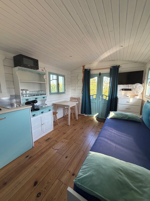 A compact room with a kitchenette, a dining area, and a bed.