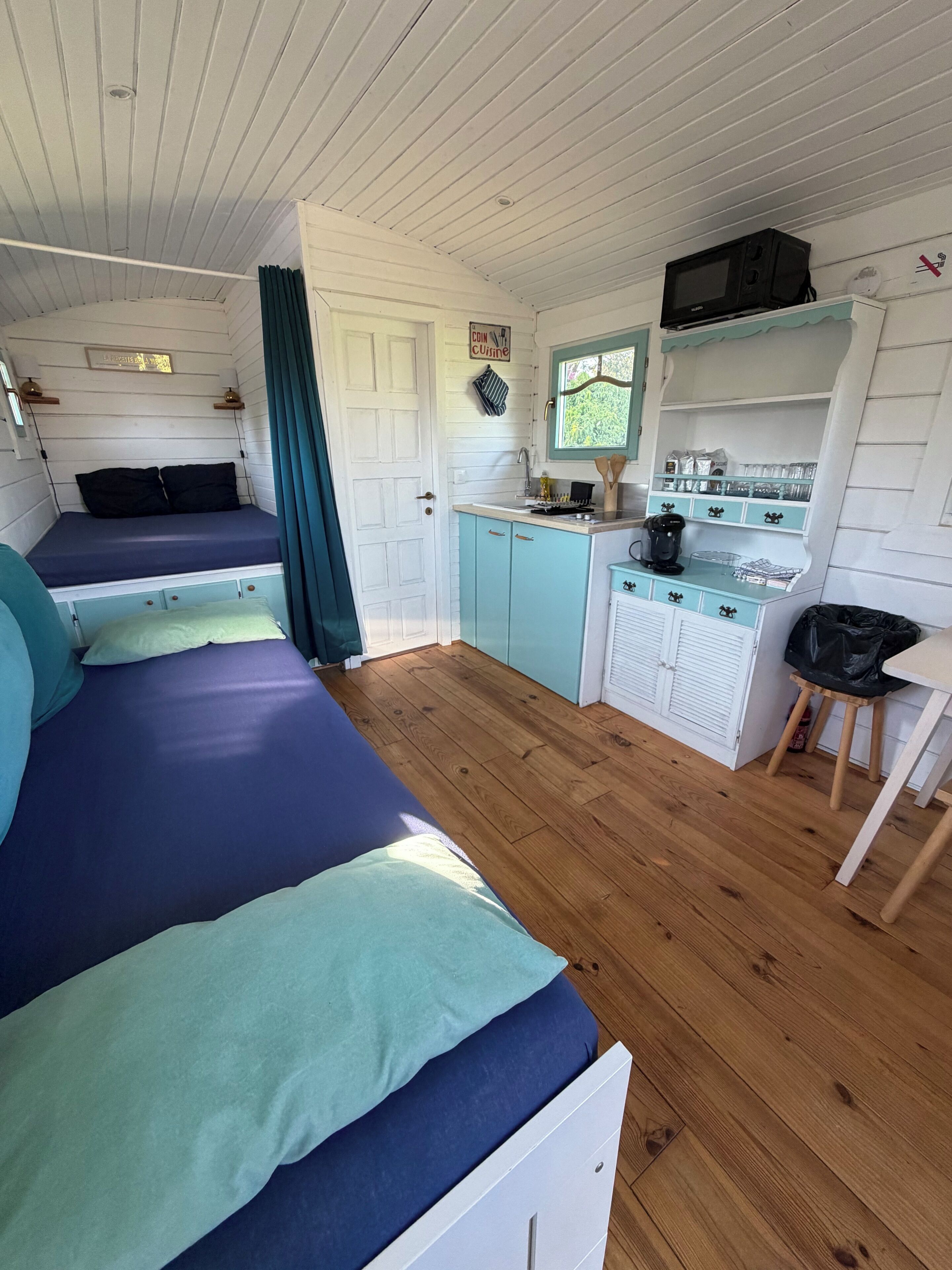 Une chambre de taille modeste comprenant deux lits, un coin cuisine et un petit espace repas.