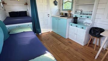 Une chambre de taille modeste comprenant deux lits, un coin cuisine et un petit espace repas.