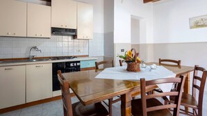Et køkken med et spisebord dækket til fire personer, en komfur og skabe.