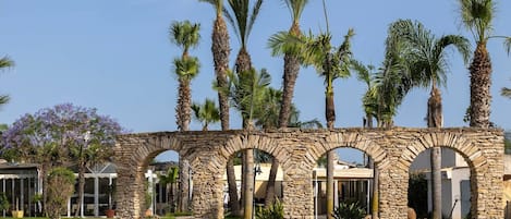Un arco de piedra con palmeras al fondo.