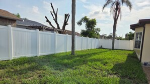 A fenced backyard with grass and trees. - Lovely 2-bedroom house with AC in cool Port Richey (Port Richey)