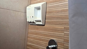 A bathroom with a wooden wall, a white soap dispenser, and a black faucet. - Hotel Del Real (Tepotzotlán)