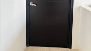 A black door with a number '1' on it, positioned in a corner with a white wall and a wooden floor. - Hotel Del Real (Tepotzotlán)