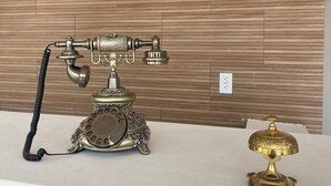 A vintage rotary dial telephone on a white surface against a wooden wall. - Hotel Del Real (Tepotzotlán)