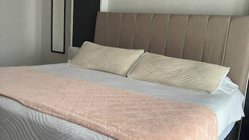Una cama con cabecera, una mesita de noche y un cuadro colgado en la pared.