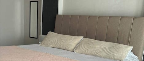 Un lit avec une tête de lit, une table de chevet et un tableau accroché au mur.