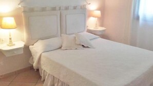 A bedroom with a bed, two bedside lamps, and a nightstand. - villa Passione (Palau)