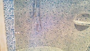 A mosaic wall with a circular pattern and a central drain. - villa Passione (Palau)