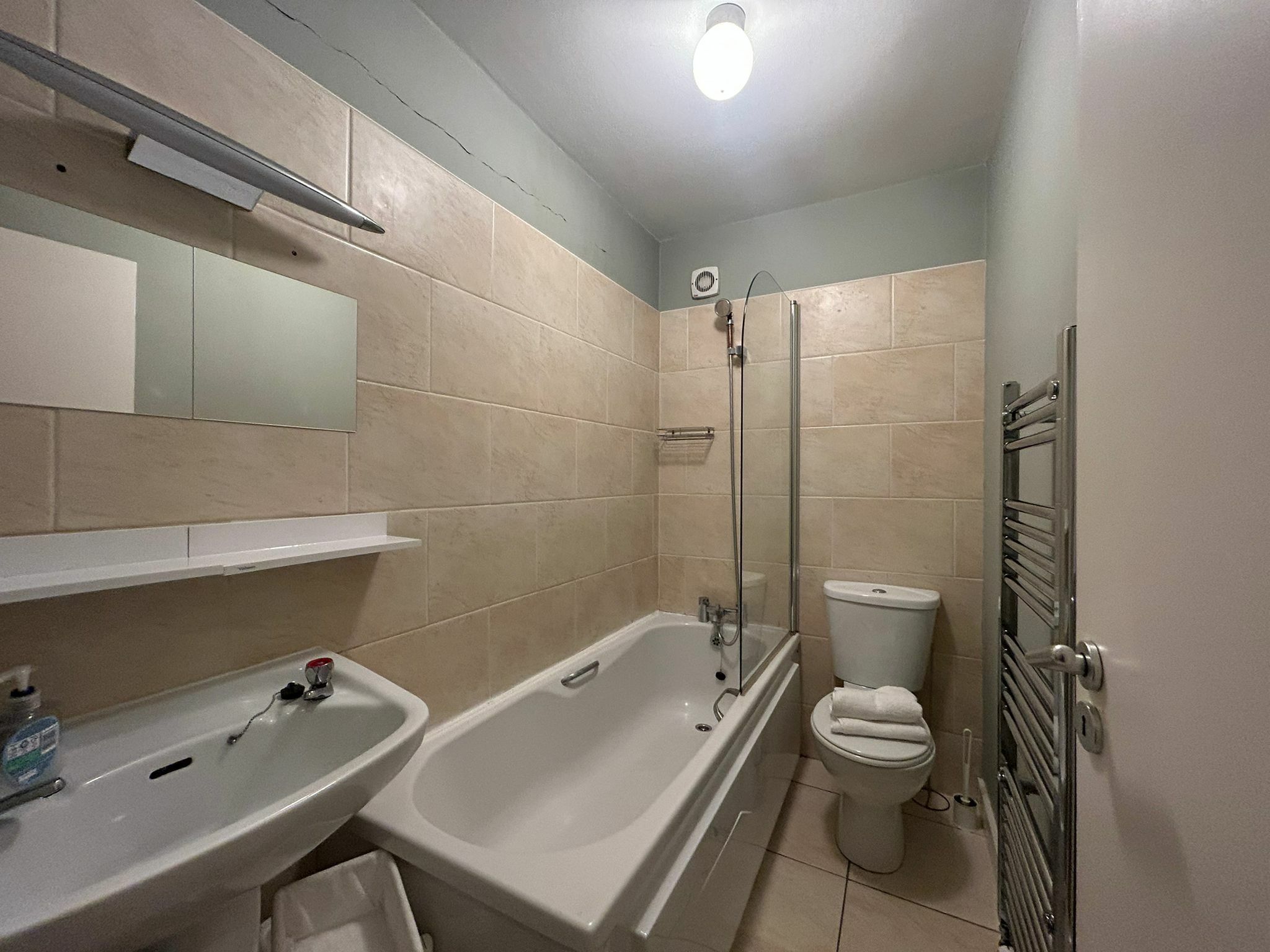 Een badkamer met een bad, toilet, wastafel en een handdoekhouder.