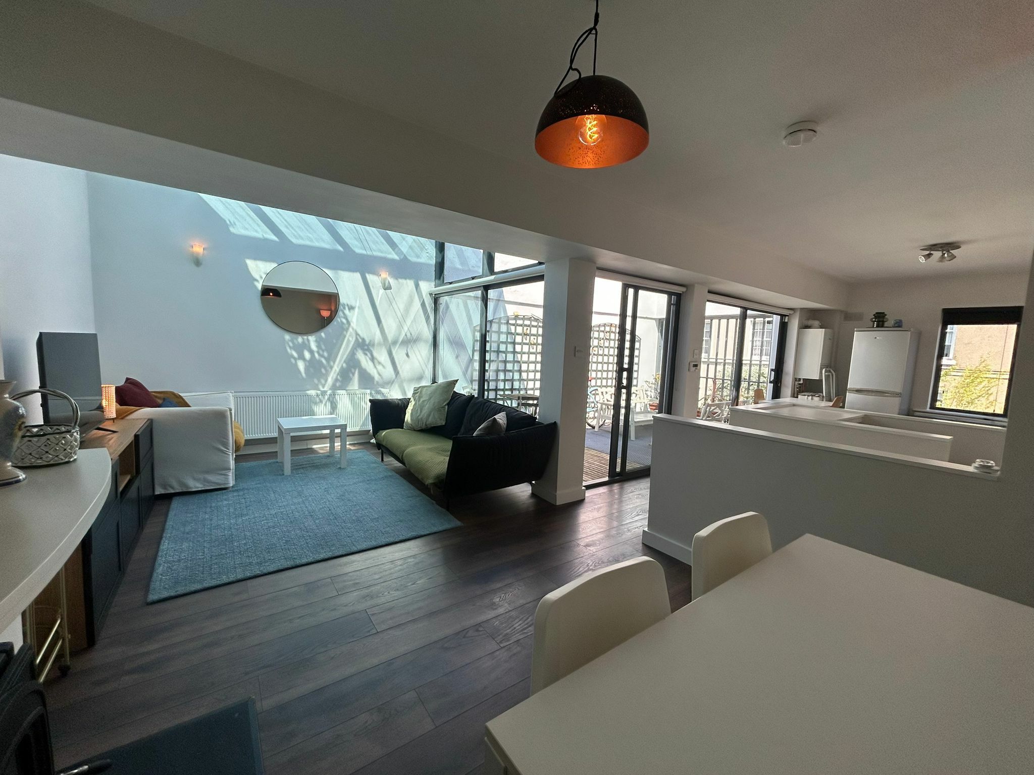 A modern living space with a sofa, dining table, and kitchen area.