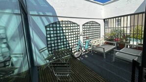 A balcony with a bicycle, a bench, and a table with potted plants. - 2BDR 2BA Upside Down House with Sunny Balcony (Dublin)