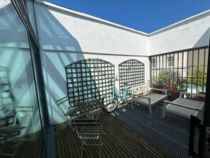 A balcony with a bicycle, a bench, and a table with potted plants. - 2BDR 2BA Upside Down House with Sunny Balcony (Dublin)