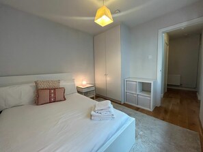Ein Schlafzimmer mit Bett, Nachttisch, Kleiderschrank und einem kleinen Schrank.