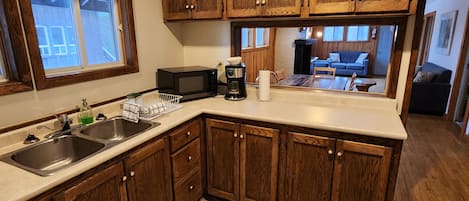 Una cocina con gabinetes de madera, un lavamanos doble, un microondas y una cafetera.