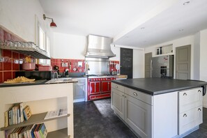 A modern kitchen with a red stove, stainless steel appliances, and a black countertop.