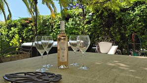 Eine Flasche C'est Top Wein und vier Gläser auf einem Tisch in einem Garten.