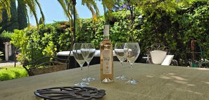 A bottle of C'est Top wine and four glasses on a table in a garden setting. - House with garden and jacuzzi - near city center (Saint-Tropez)