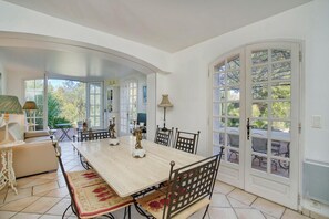 A dining area with a large table, chairs, and a sofa. There are decorative items on the table and a lamp on the side. - House with garden and jacuzzi - near city center (Saint-Tropez)
