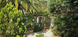 Ein Gartenweg, der zu einem Gebäude mit weißer Fassade und Rundbogenfenstern führt.