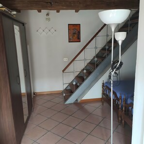 A staircase with a metal railing and a wooden handrail, leading to a landing with a white wall and a framed picture.