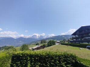 A mountainous landscape with a clear sky, a wooden cabin, and a large building with balconies. - Combloux studio with Mont Blanc view (Combloux)