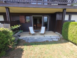 A patio area with two white folding chairs, a wooden fence, and a well-maintained hedge. - Combloux studio with Mont Blanc view (Combloux)