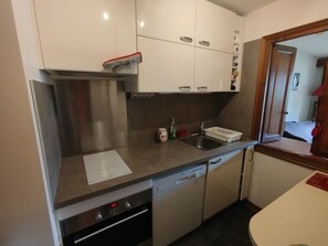 Eine kleine Küche mit Backofen, Spüle und Geschirrspüler.