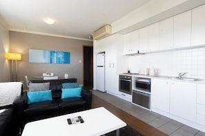 A modern kitchen with white cabinets, a built-in oven, and a microwave. - Lovely 2BR Apartment in West Perth with Parking! (West Perth)