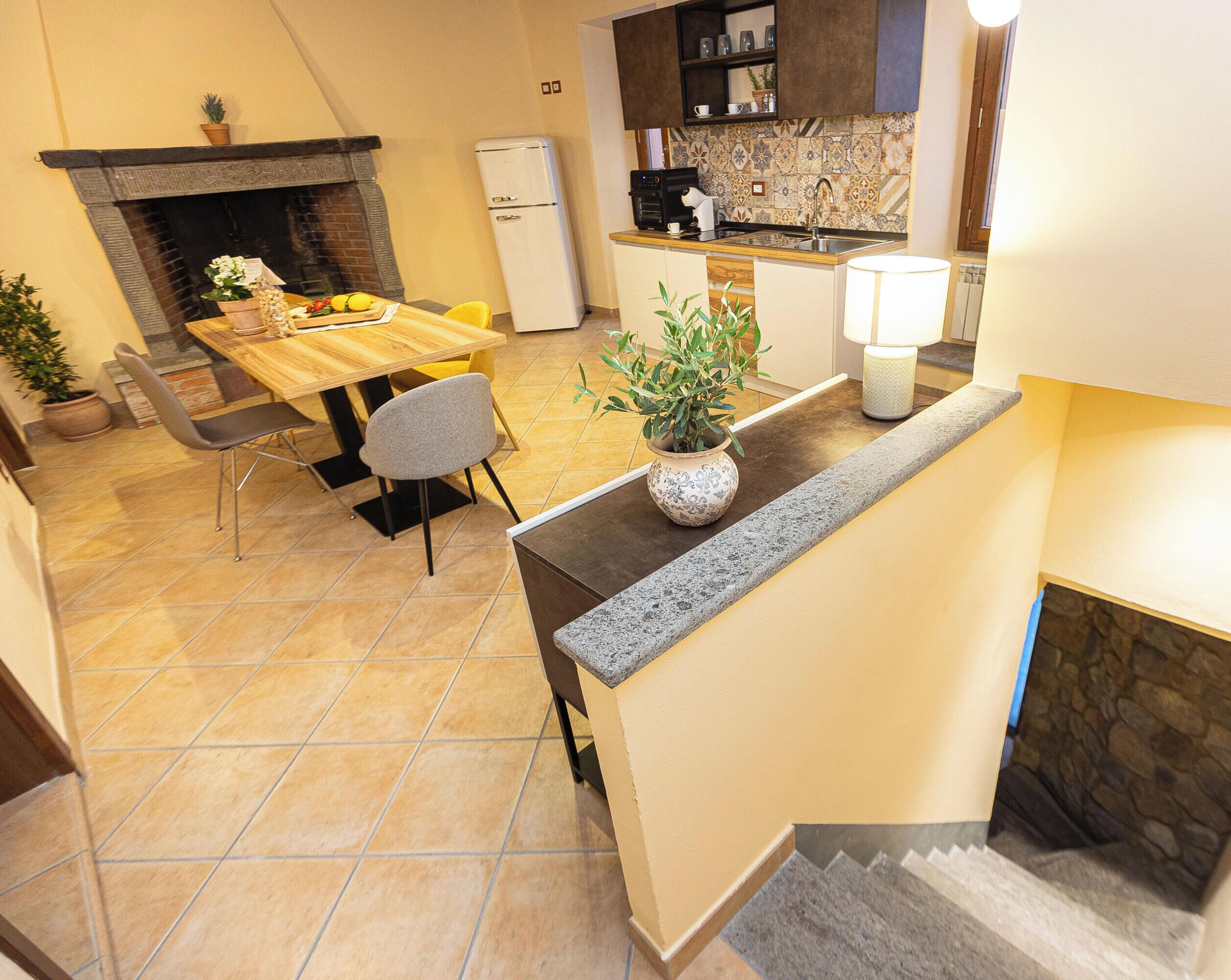 A kitchen with a dining area, a fireplace, and a staircase.