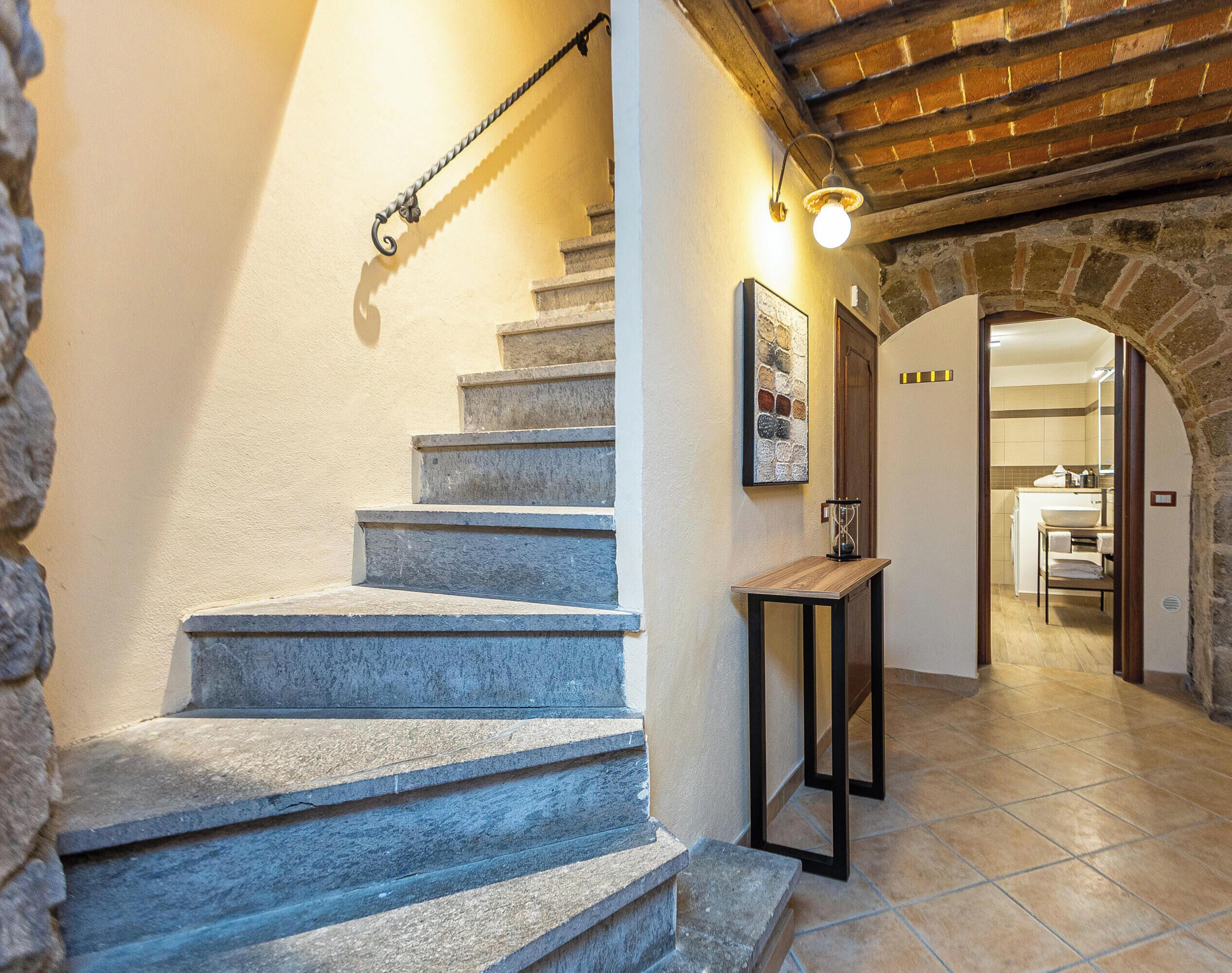 Una escalera de piedra que lleva a un baño con piso de azulejos y puerta de madera.