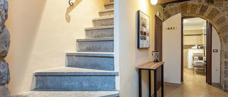 A stone staircase leading to a bathroom with a tiled floor and a wooden door.