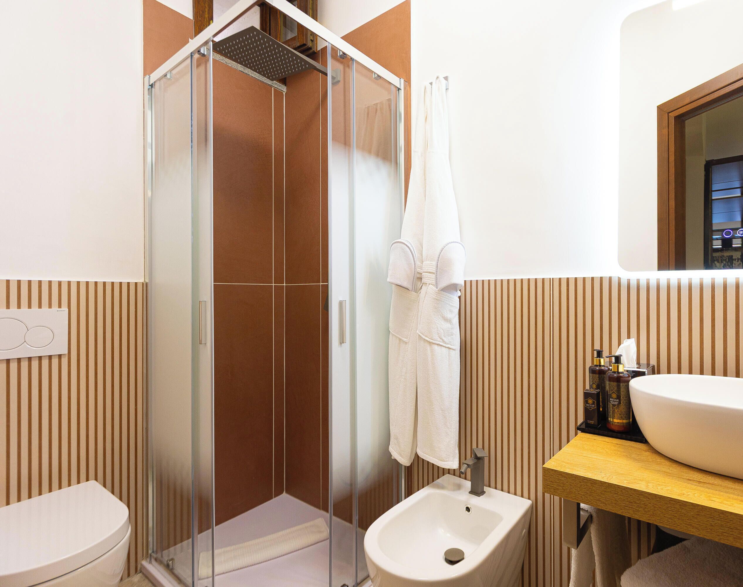 Ein Badezimmer mit Duschkabine, Bidet, Waschbecken und Handtuchhalter.