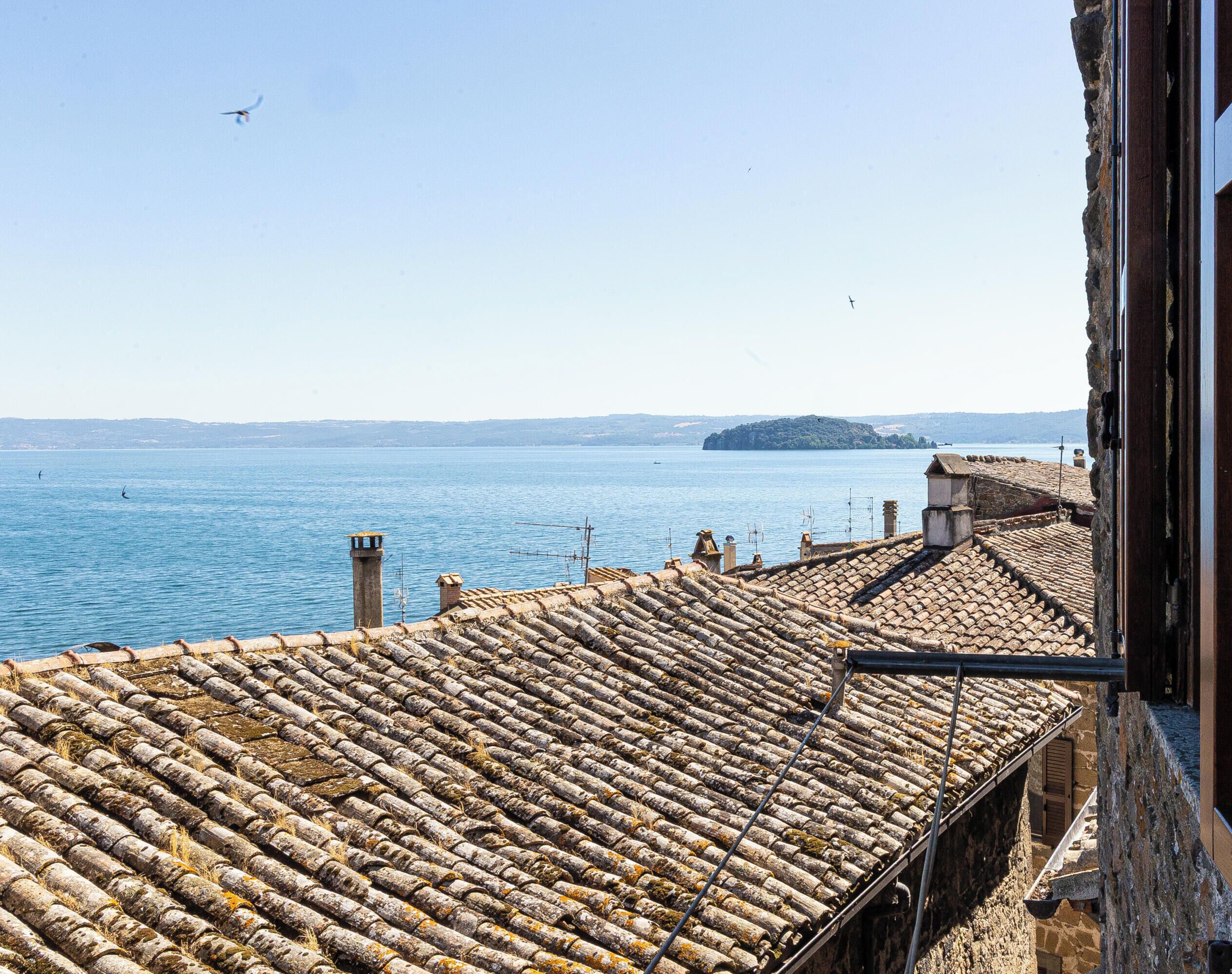 Une vue sur la côte, avec un toit recouvert de tuiles, un ciel dégagé et une île lointaine.