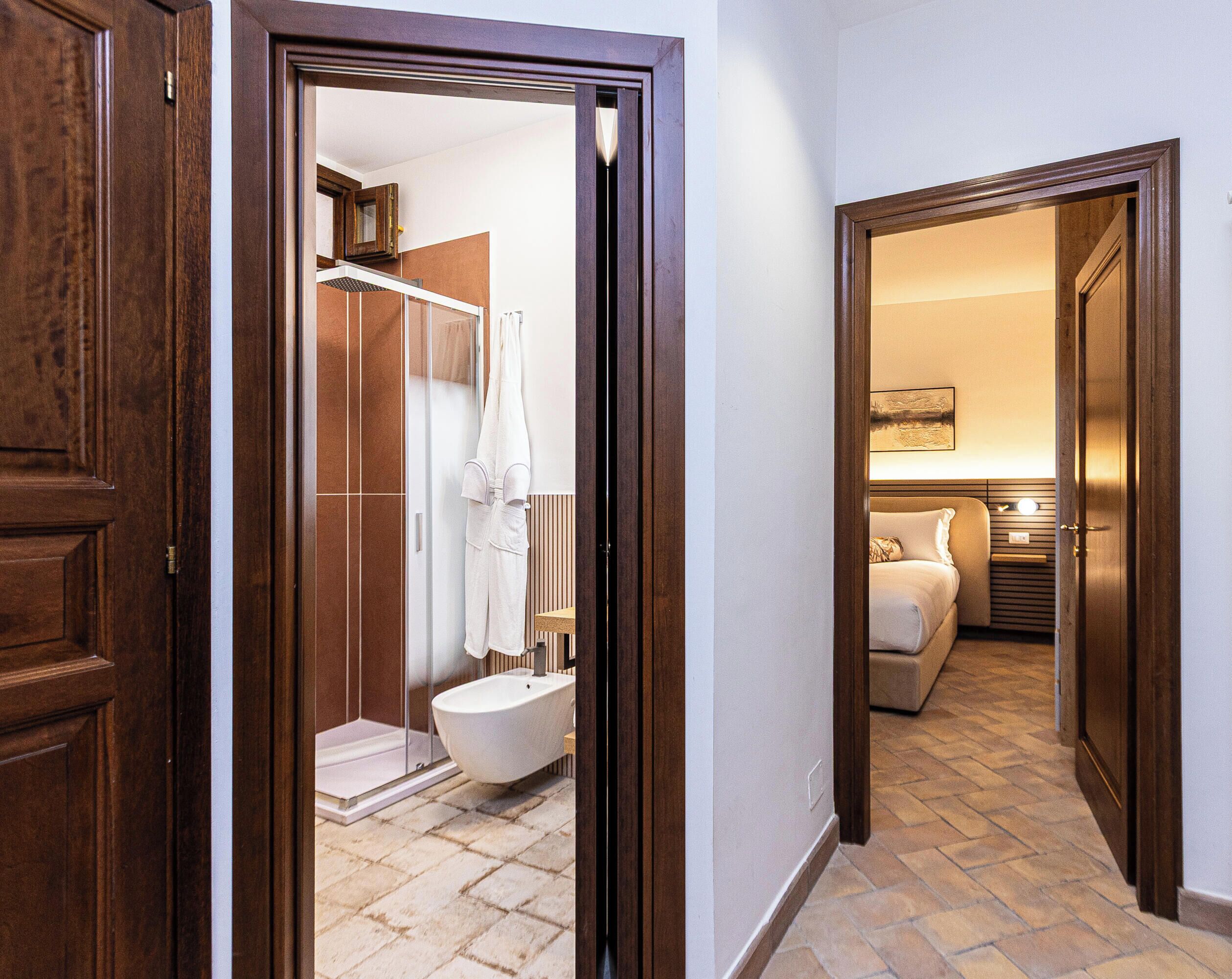 Un corridoio che conduce a un bagno con doccia, WC e lavabo.