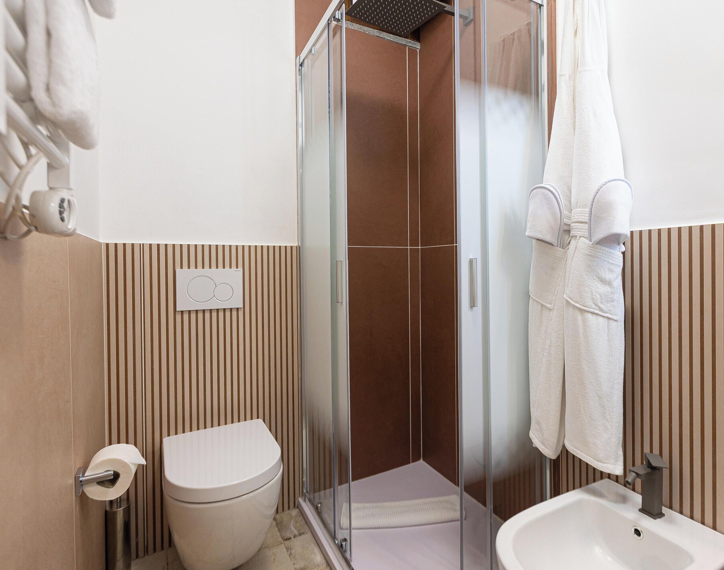A bathroom with a toilet, a glass shower enclosure, and a sink.