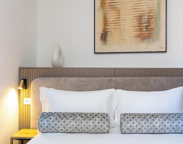 A hotel room with a bed, pillows, a wall-mounted light, and a painting. - Marta Lake Albergo Diffuso & Spa (Marta)