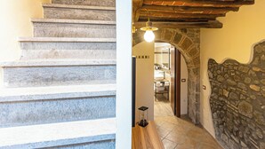 A staircase with stone steps leading to a room with a stone wall and a wooden ceiling.