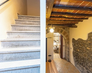 A staircase with stone steps leading to a room with a stone wall and a wooden ceiling.
