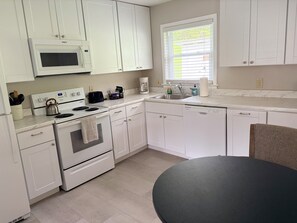 A modern kitchen with white cabinetry, a built-in microwave, a kettle, a coffee maker, and a dishwasher. - Dog-friendly 2 bedroom house with king bed in Oak Ridge (Oak Ridge)