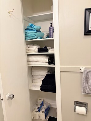 A bathroom with a toilet paper holder, a towel rack, and a shelf with towels. - Dog-friendly 2 bedroom house with king bed in Oak Ridge (Oak Ridge)
