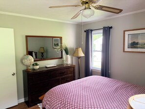 A bedroom with a bed, dresser, mirror, globe, lamp, and a window with curtains. - Dog-friendly 2 bedroom house with king bed in Oak Ridge (Oak Ridge)