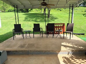 An outdoor patio with a covered seating area, including chairs and a table, overlooking a grassy yard. - Dog-friendly 2 bedroom house with king bed in Oak Ridge (Oak Ridge)