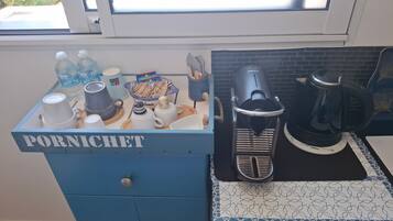 Un plan de travail de cuisine avec une machine à café, une bouilloire et un meuble bleu portant l’inscription « PORNICHET ».