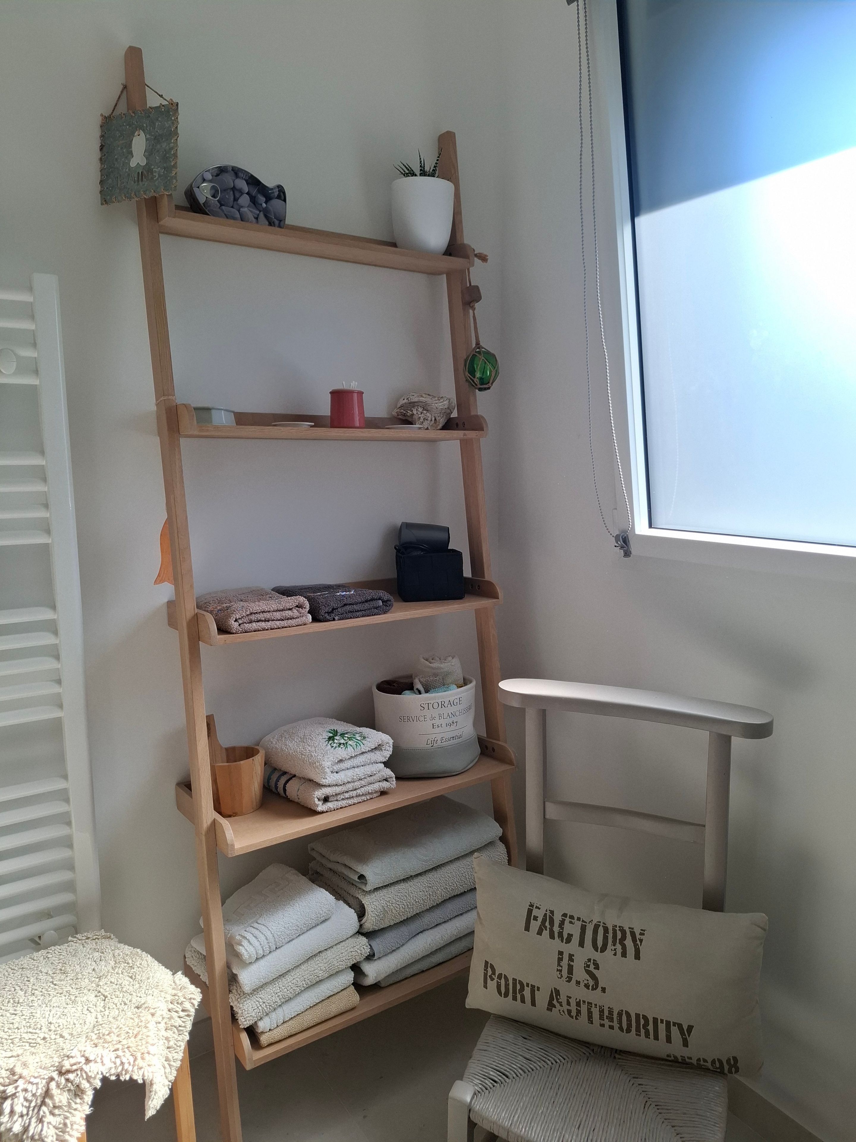 A wooden shelf with folded towels, a potted plant, and a sign reading 'FACTORY I.S. PORT AUTHORITY.'