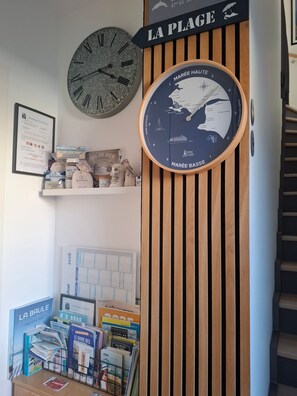 Een muur met een grote klok, een bord waarop 'LA PLAGE' staat en een getijdenklok met de tekst 'MARÉE BASSE'.