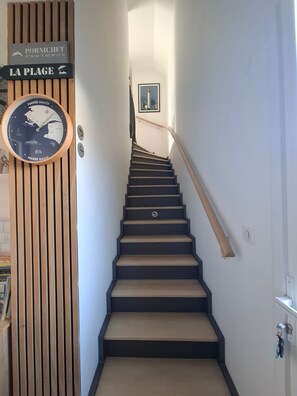 Un escalier avec une rampe en bois et une horloge au mur.